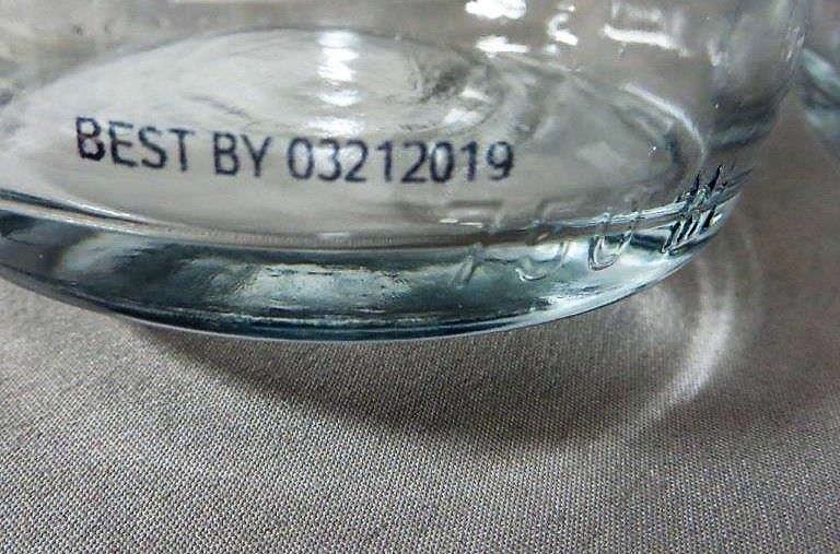 Expiry date code on clear glass bottle, mark made with a Matthews Marking Systems inkjet